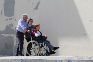 two people pushing a woman in a wheelchair